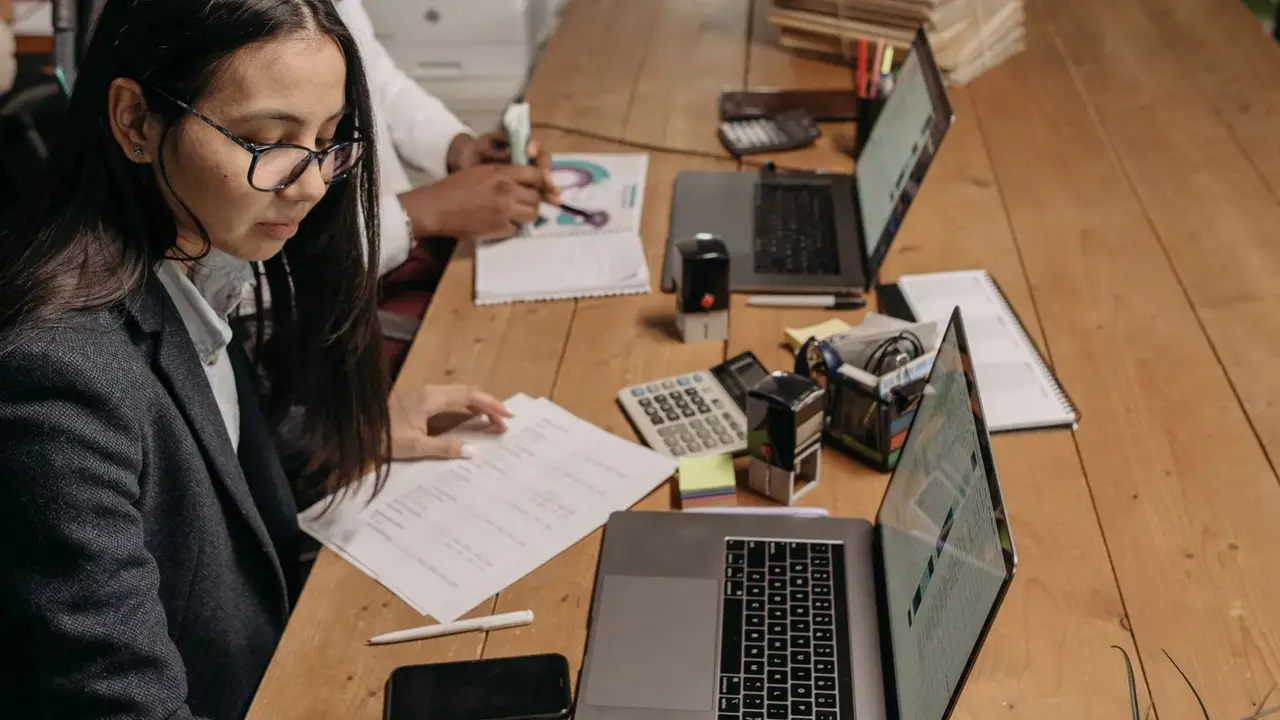 A new employee being shown workplace pension paperwork across a desk.